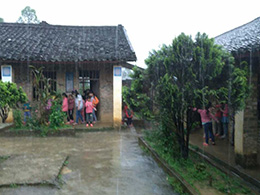 暴雨中，教室里出現漏水情況，學生們在屋檐下避雨
